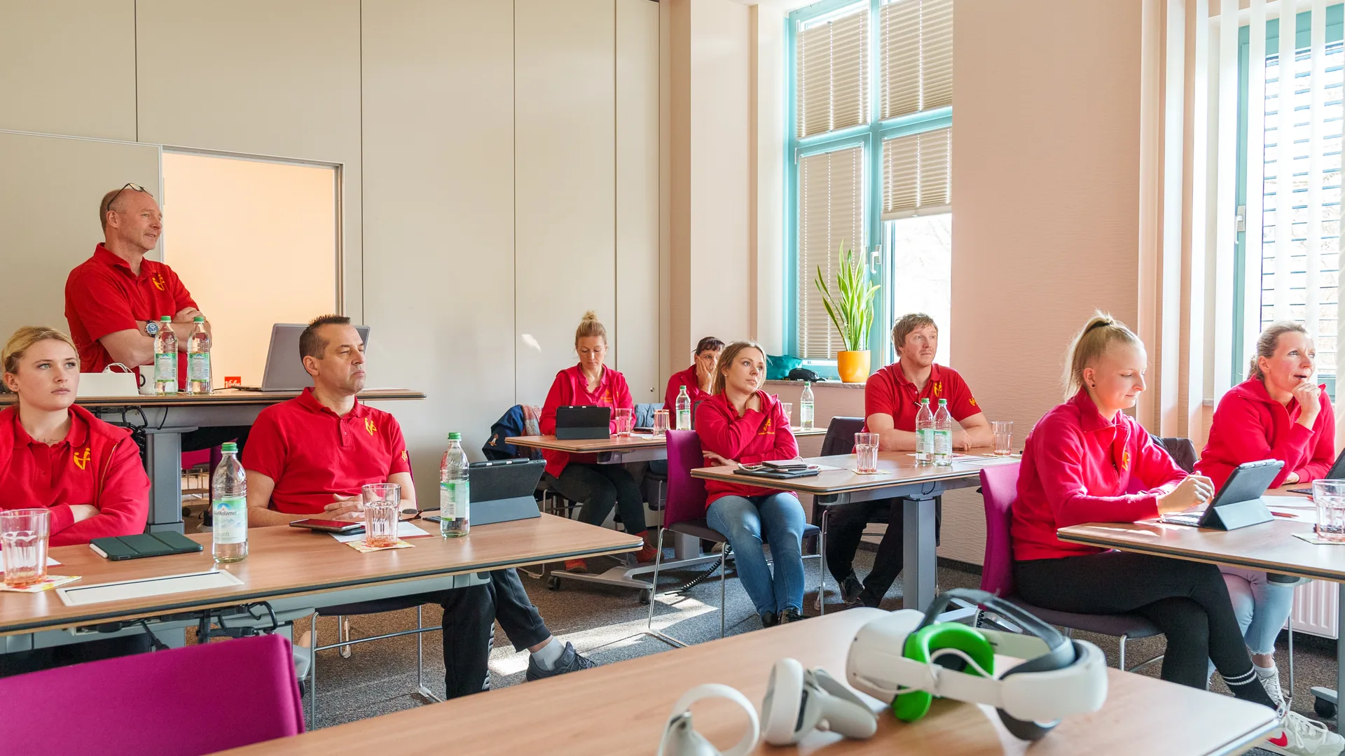 Mitarbeitende in roten Poloshirts im Schulungsraum bei einer internen Fortbildung