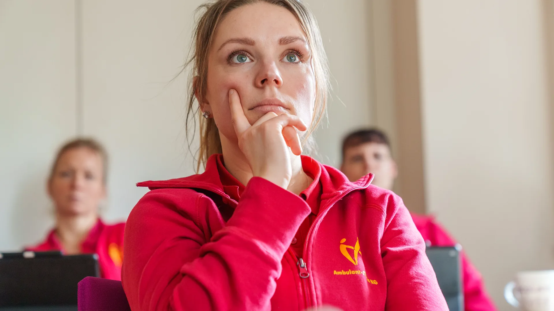 Mitarbeiterin im roten Poloshirt hört nachdenklich zu